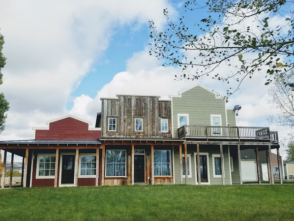 A row of three-story buildings with a covered porch and a fenced yard.