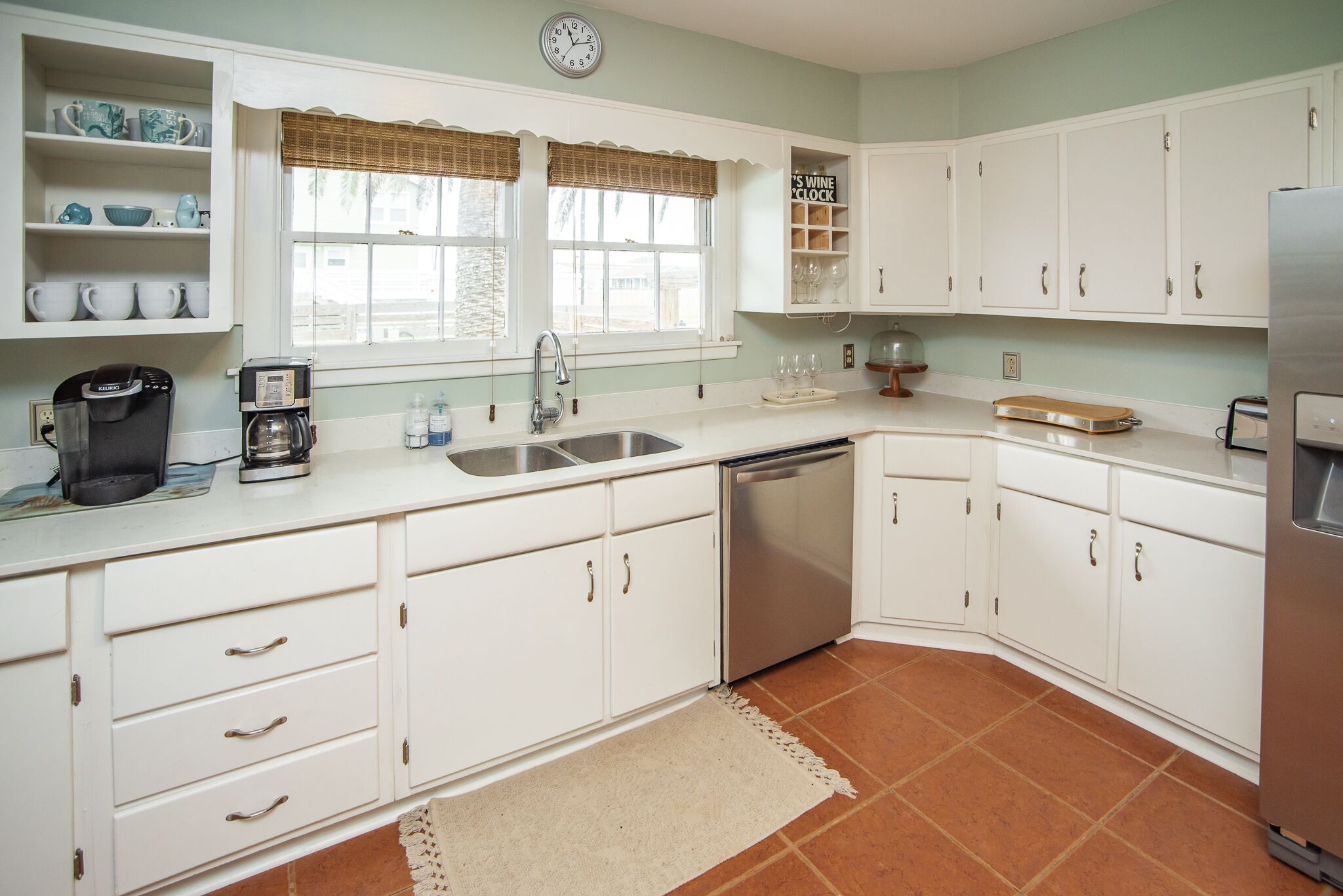 A kitchen with white cabinets, a sink, a dishwasher, and a coffee maker.