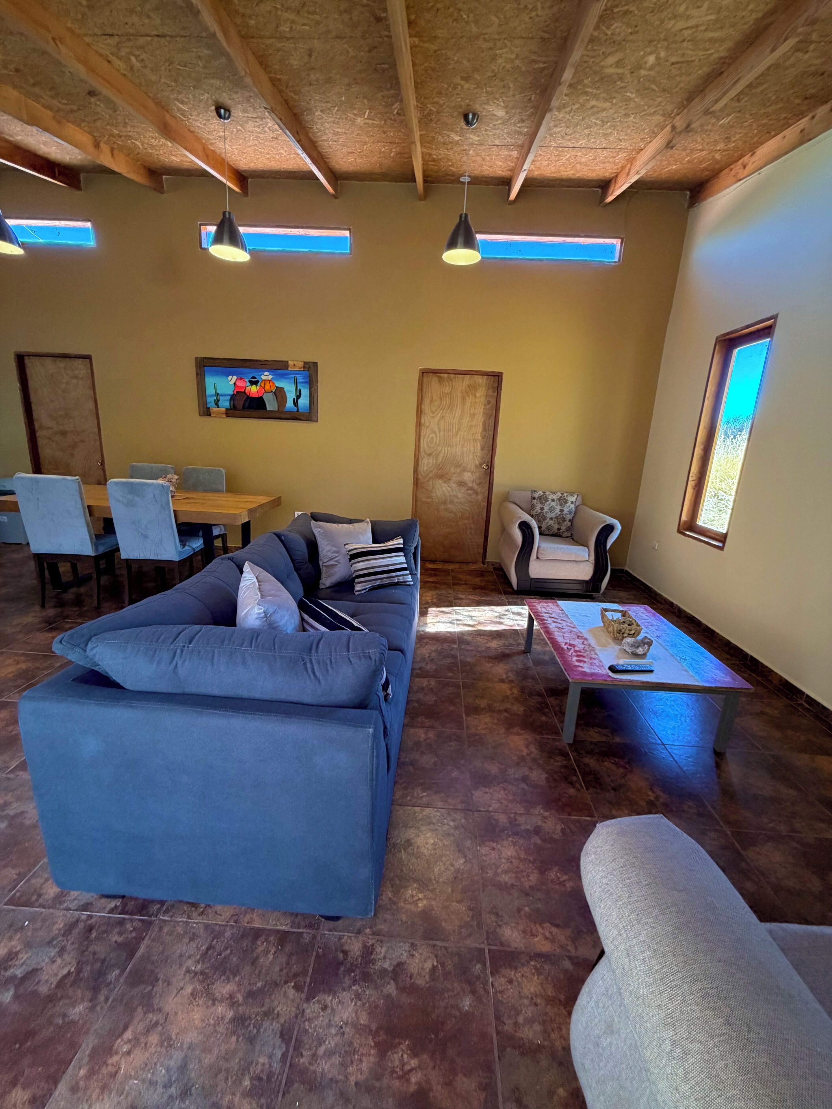 A spacious living area with a blue sofa, a dining table, and a coffee table.