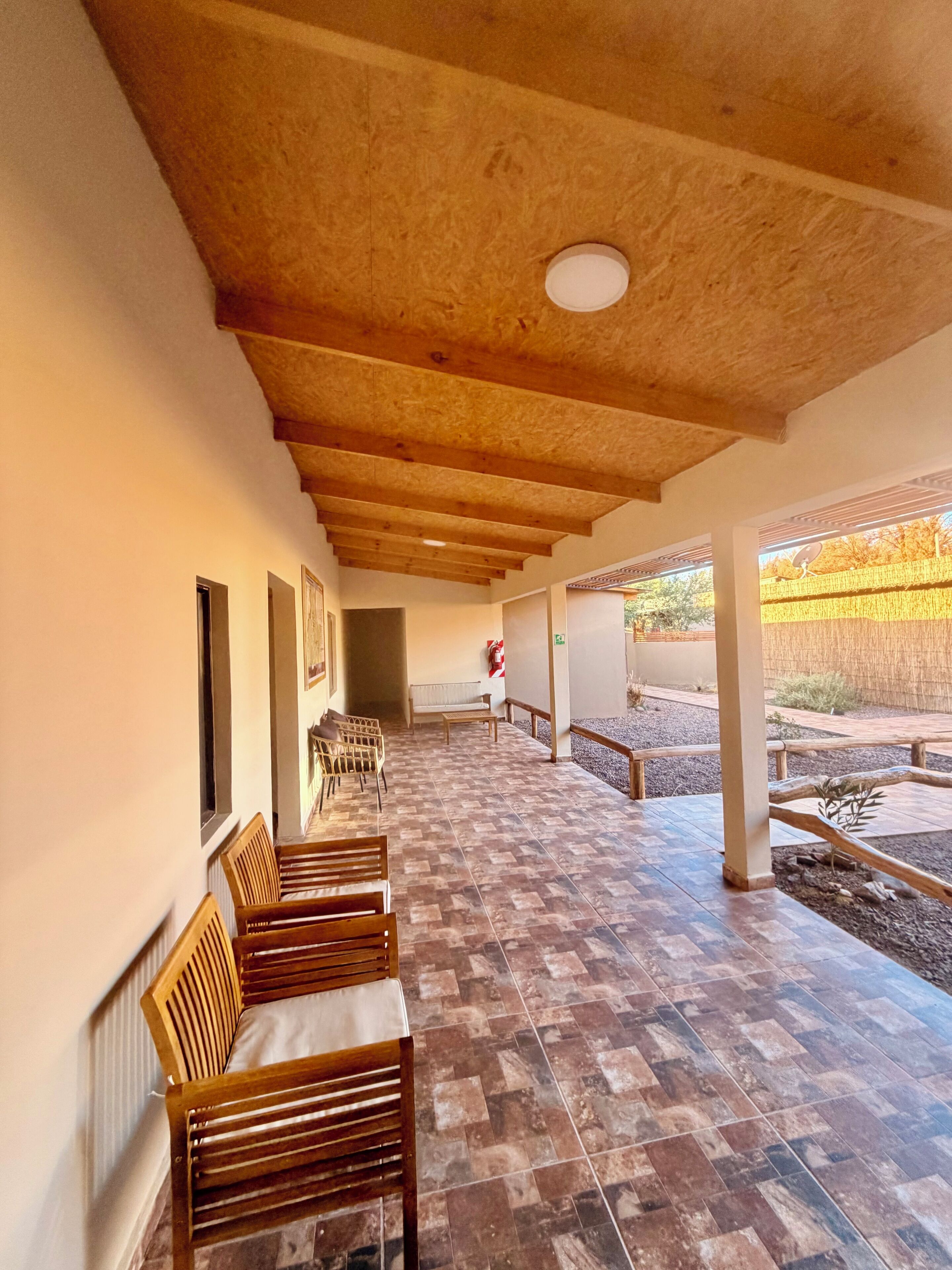 A covered outdoor seating area with wooden benches and a tiled floor.
