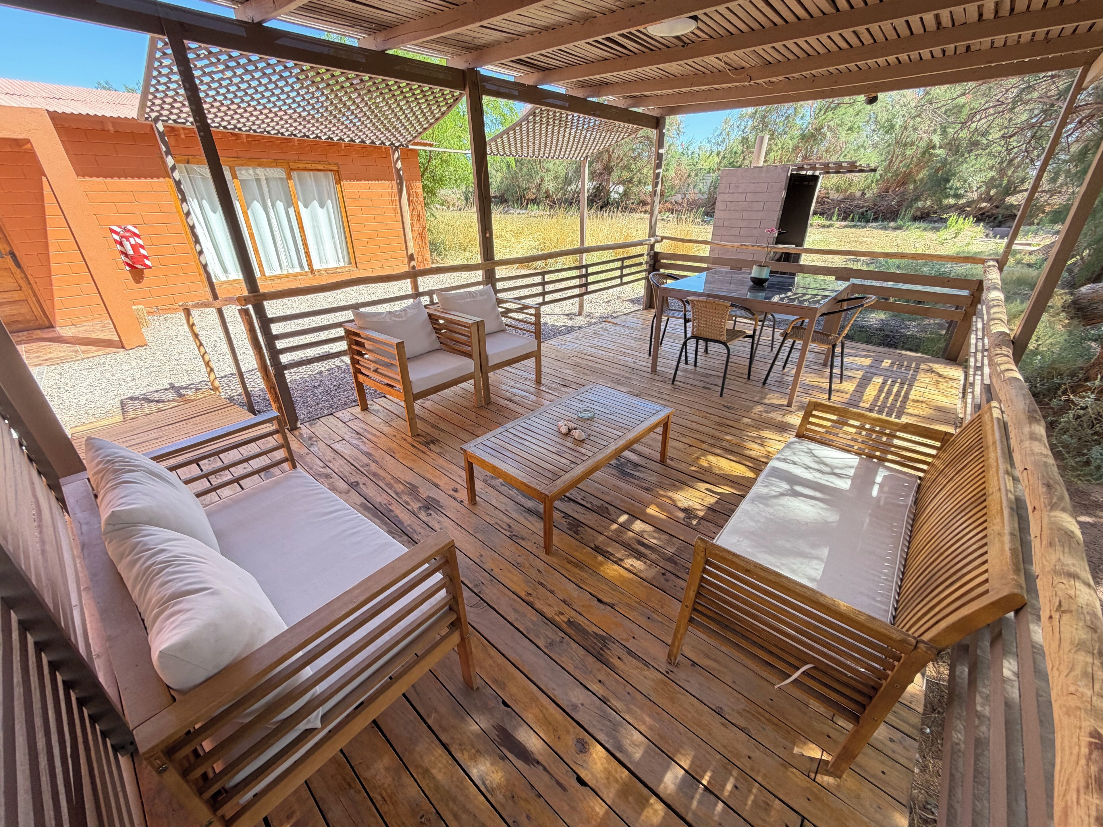 A wooden deck with outdoor furniture, including sofas and a table, and a covered area with a view of the surrounding landscape.