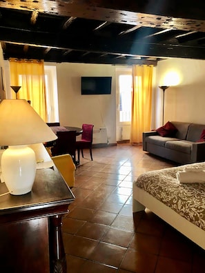 Una habitación con una cama, un sofá, una mesa con una lámpara, un televisor y una silla.