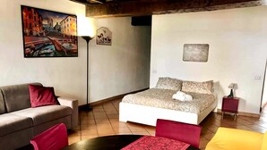 Un dormitorio con cama, sofá, mesa y lámpara.