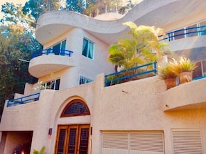 Un bâtiment moderne à la façade incurvée, doté de nombreux balcons et agrémenté de plantes en pot.