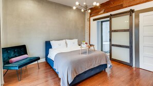 A bedroom with a bed, a bench, a small table with items, and a sliding glass door. -  SJ4 Exclusive  Private Historic Contemporary suites  (San Antonio)