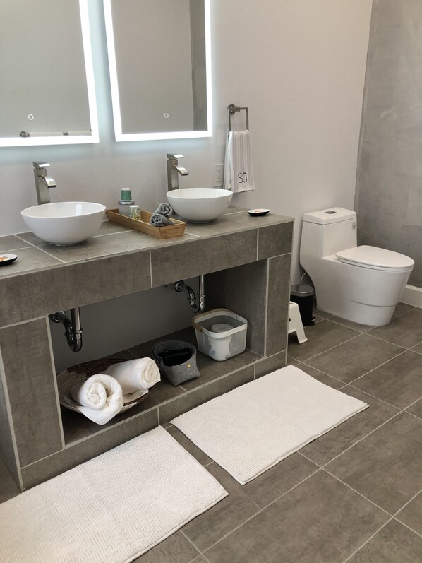 Une salle de bain moderne avec un double lavabo, un grand miroir, des toilettes et un porte-serviettes.