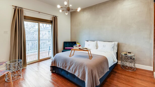 A modern bedroom with a large bed, a small table, a chair, and a view of the outdoors. -  SJ4 Exclusive  Private Historic Contemporary suites  (San Antonio)