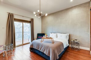 Une chambre à coucher moderne avec un grand lit, une petite table, une chaise et une vue sur l’extérieur.
