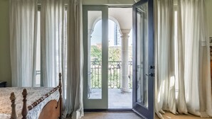 Une chambre à coucher avec un lit, une porte donnant sur un balcon et des rideaux.