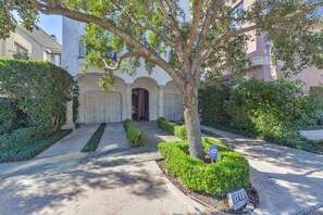 A residential property with a well-maintained front yard, a large tree, and a gated entrance.
