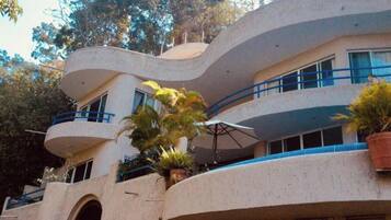 A multi-story building with balconies, potted plants, and a curved architectural design.