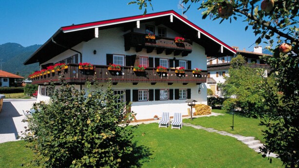 A traditional chalet-style building with a red roof and balconies adorned with flowers. - Apartment No. 2, Jenner, for 1 to 2 people, 40 sqm, 1 bedroom, balcony (Schönau am Königssee)