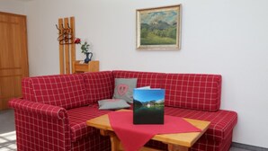 A red checkered sofa with a wooden table and a painting on the wall. - Apartment No. 2, Jenner, for 1 to 2 people, 40 sqm, 1 bedroom, balcony (Schönau am Königssee)