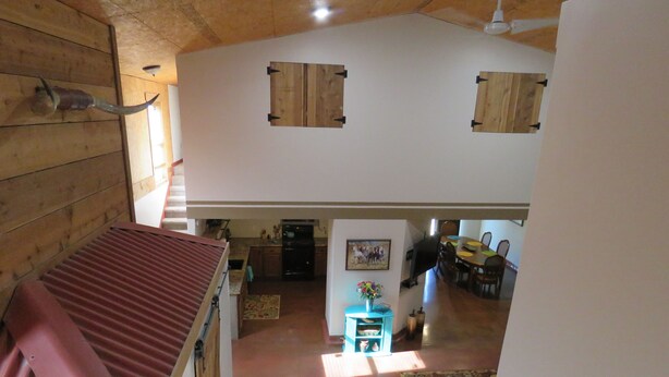 Een ruime binnenruimte met een hoge plafond, houten wanden en een eethoek met een tafel en stoelen.