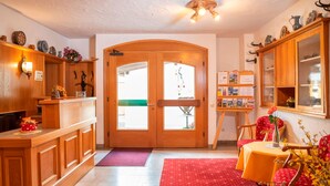 A reception area with a wooden counter, a red carpet, and a wooden door with glass panels. - Apartment for 1-2 people, separate bedroom, shower / toilet, balcony, 40 sqm (Schönau am Königssee)