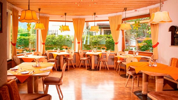 A restaurant with wooden ceiling and tables set for dining, large windows with curtains, and a view of greenery outside. - Apartment for 1-2 people, separate bedroom, shower / toilet, balcony, 40 sqm (Schönau am Königssee)