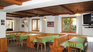 A dining area with wooden benches and tables, a television, and a window with a view of greenery. - Stunning private villa for 41 guests with WIFI, TV and terrace (Wildschönau)
