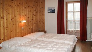 A room with wooden walls, a bed with white bedding, a wall-mounted light, and a window with red curtains. - Stunning private villa for 41 guests with WIFI, TV and terrace (Wildschönau)
