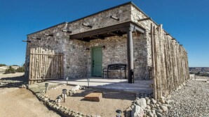 Ein Steinhaus mit grüner Tür, einer Bank und einer Pergola.
