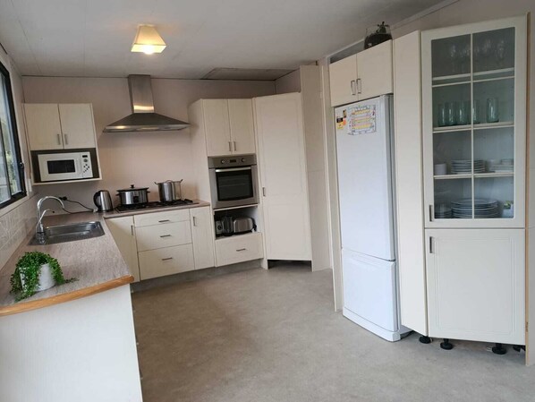 A compact kitchen with white cabinets, a microwave, stove, oven, and a refrigerator.