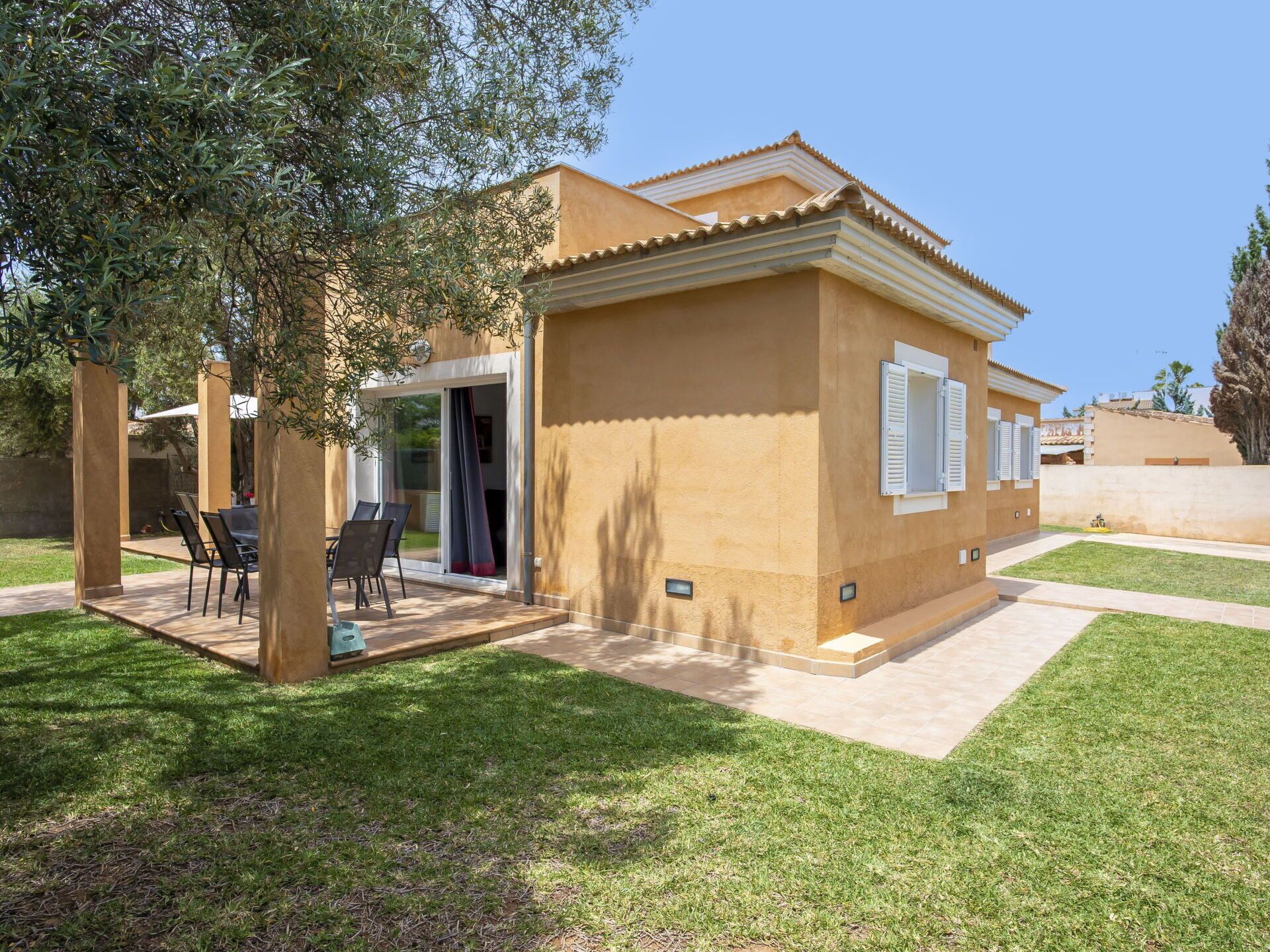 A single-story house with a patio, a covered outdoor seating area, and a lawn.