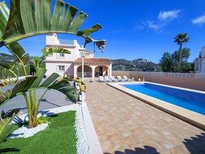 A pool area with a tiled deck, a lounge chair, and a building with a tiled roof in the background. - Wonderful private villa for 11 guests with WIFI, A/C, private pool, TV, patio and pets allowed (Calpe)
