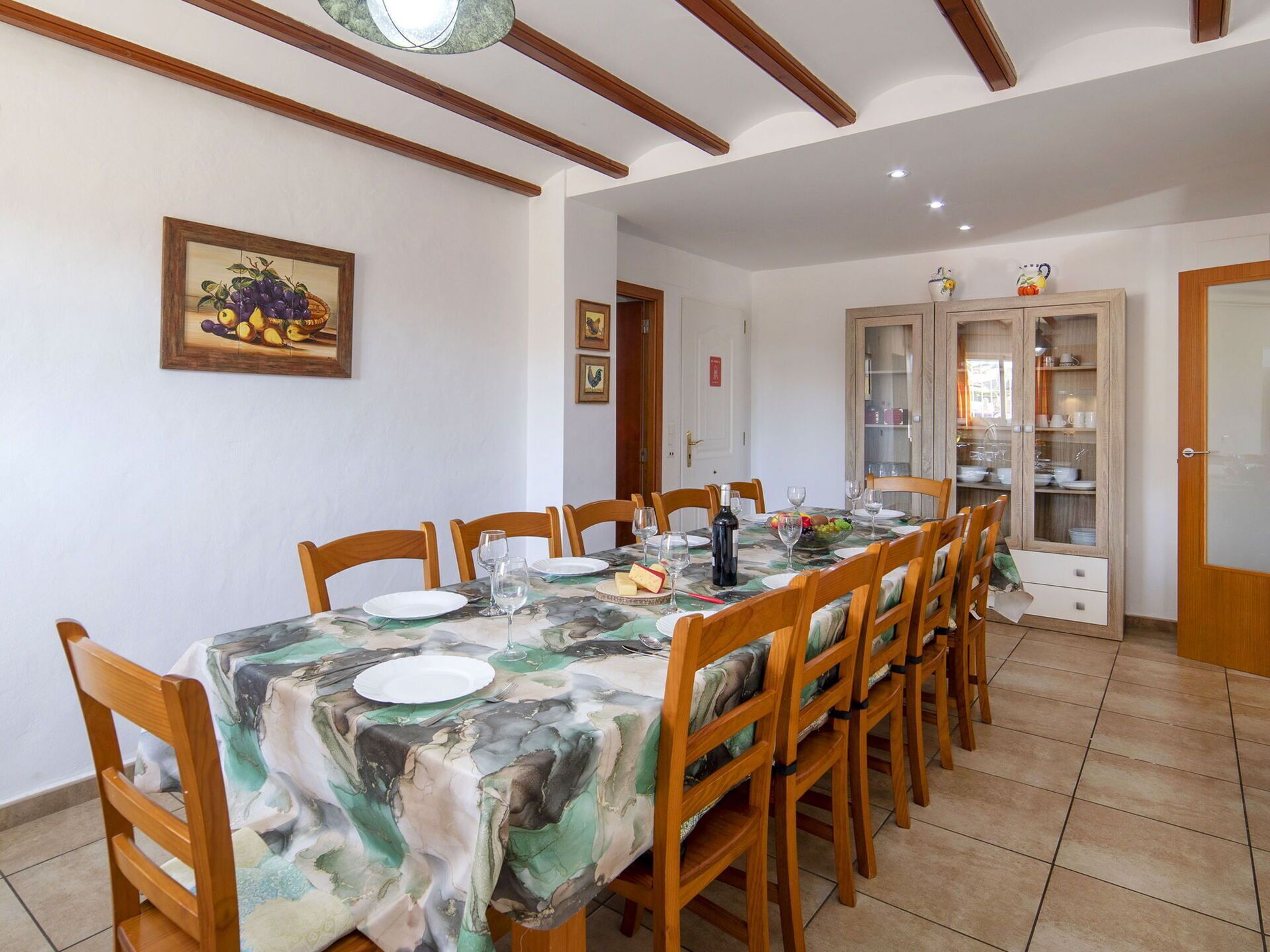 A dining area with a table set for six, wooden chairs, and a cabinet with glass doors.