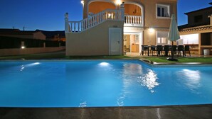 Une maison à deux étages dotée d’une piscine, d’un balcon et d’un patio aménagé avec du mobilier d’extérieur.