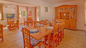 A dining area with a wooden table and chairs, a television, and a cabinet with glass doors. - Wonderful private villa for 11 people with WIFI, private pool, A/C, TV, terrace and pets allowed (Benissa)