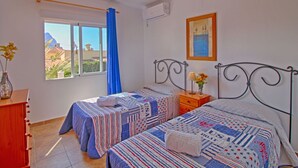 A bedroom with two beds, a window with a view, a painting on the wall, and an air conditioning unit. - Wonderful private villa for 11 people with WIFI, private pool, A/C, TV, terrace and pets allowed (Benissa)