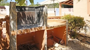 An outdoor grill with a stone base, surrounded by a garden with rocks and plants. - Wonderful private villa for 11 people with WIFI, private pool, A/C, TV, terrace and pets allowed (Benissa)