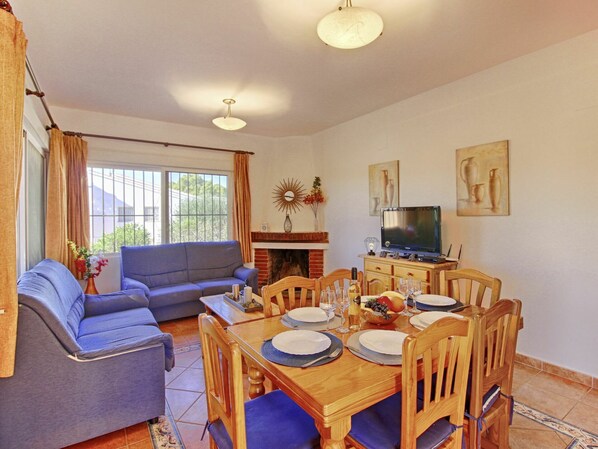 Comedor con una mesa de madera dispuesta para cuatro personas, rodeado de sillas de madera.