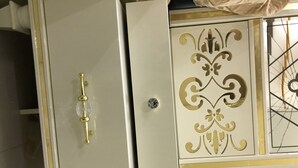 Un mueble blanco con un tirador dorado y un panel decorativo.