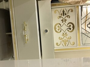 A white cabinet with a gold handle and decorative panel.