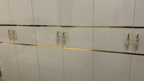 Un conjunto de armarios blancos con detalles y tiradores dorados.