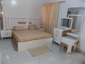 Une chambre à coucher comprenant un lit, des tables de chevet, une commode, un miroir et un tapis à motifs.