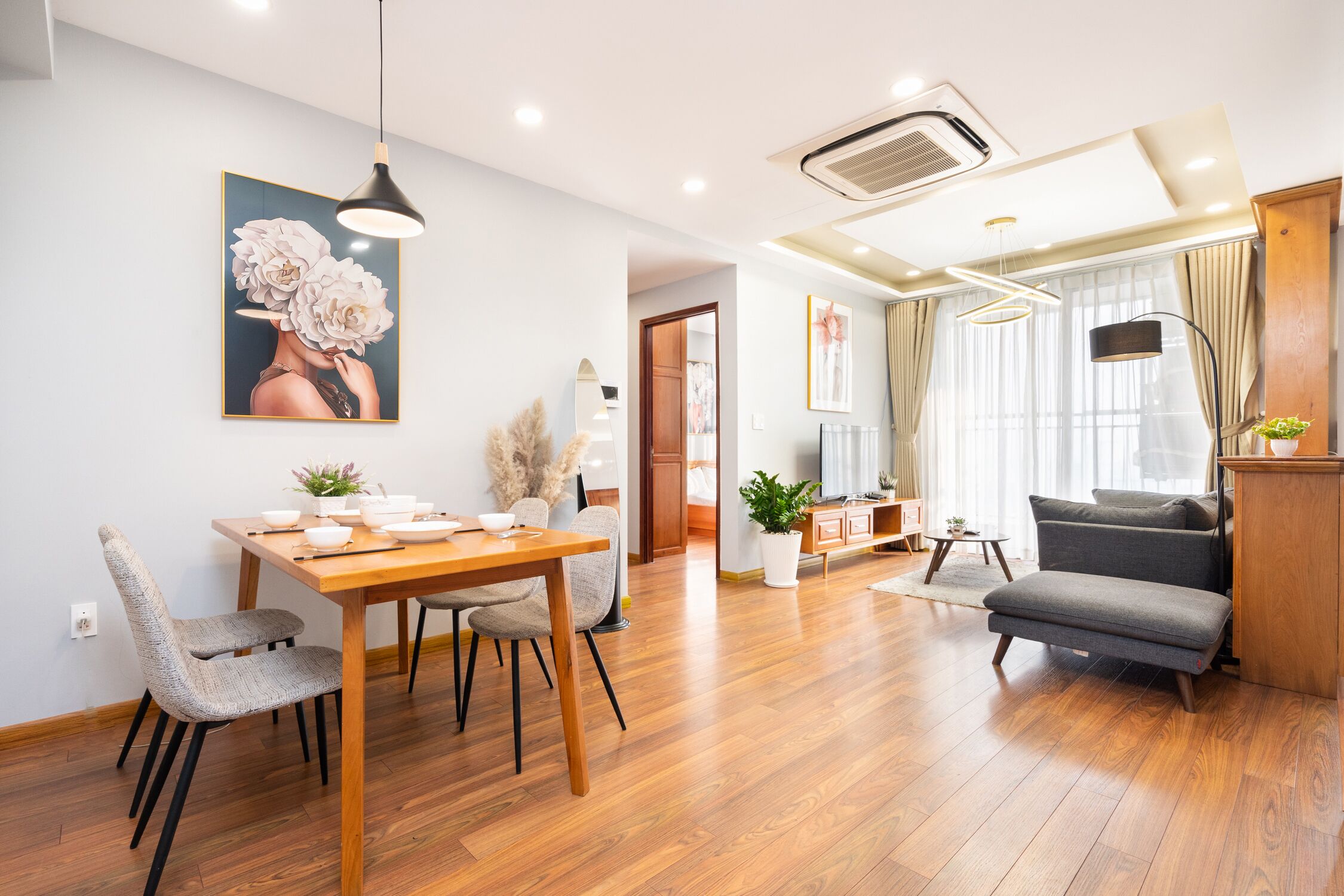 Una sala de estar moderna con una mesa de comedor de madera, sillas tapizadas de color gris, un sofá gris y un mueble de madera.