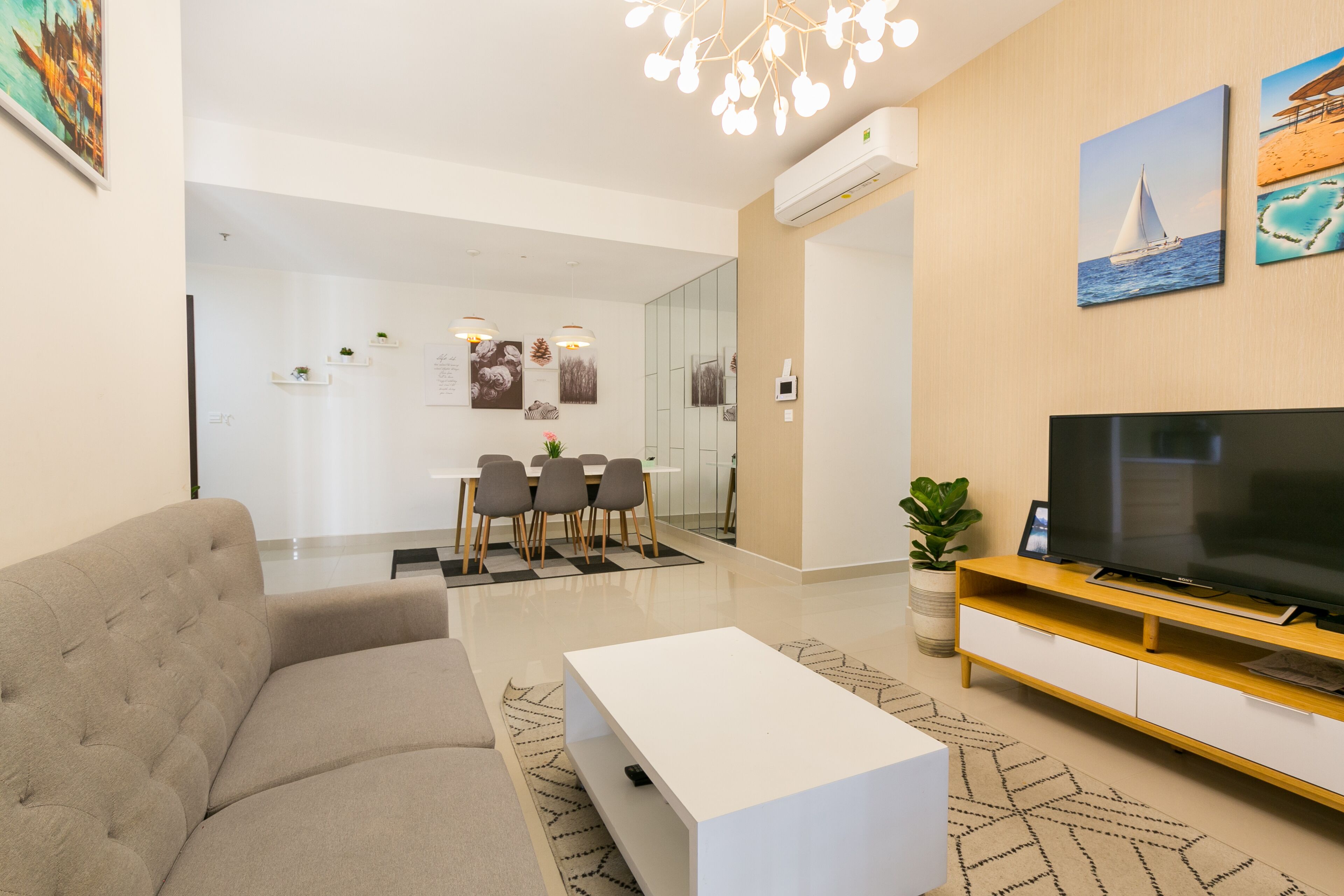 Un salon moderne comprenant un canapé, une table basse, un téléviseur et un coin repas avec des chaises et une table.