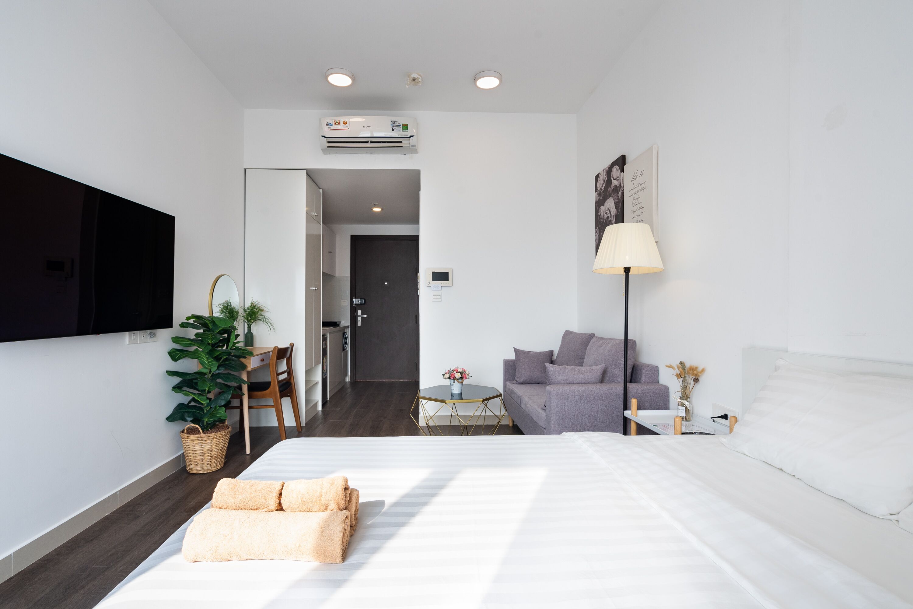 Une chambre d’hôtel moderne, dotée d’un grand lit, d’un bureau, d’un canapé et d’un téléviseur fixé au mur.