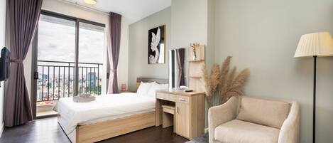 Habitación de hotel moderna con una cama grande, un escritorio, una silla y vistas a la ciudad desde un balcón.