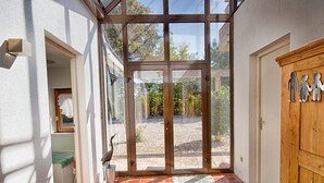 Ein geräumiger Eingangsbereich mit Fliesenboden, einer Holztür und Blick auf einen Garten durch große Glasüren.