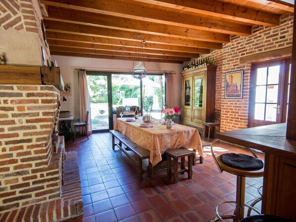 A rustic dining area with a wooden table, benches, and a brick wall.