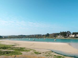 A beach with boats, a sandy shore, and buildings in the background.