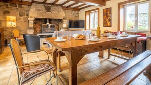 Un coin repas rustique avec une cheminée en pierre, des poutres en bois et un téléviseur.