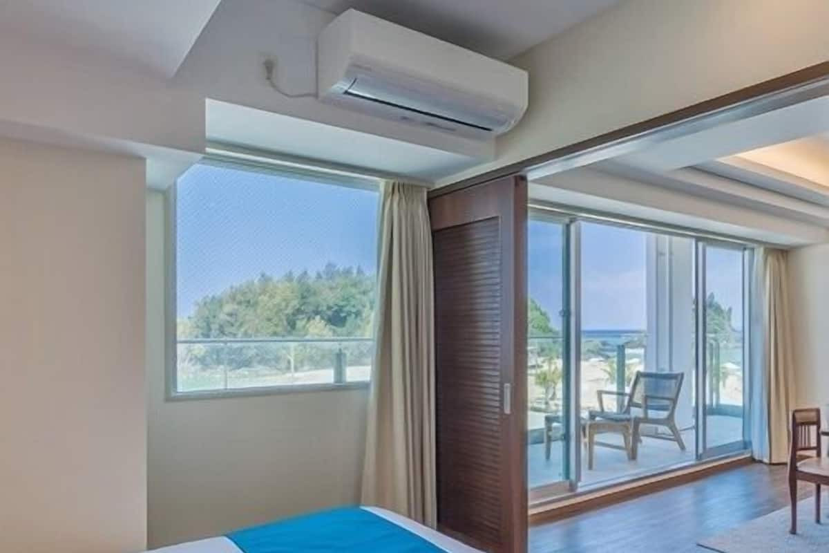 A hotel room with a bed, a large window, and a sliding glass door leading to an outdoor area.