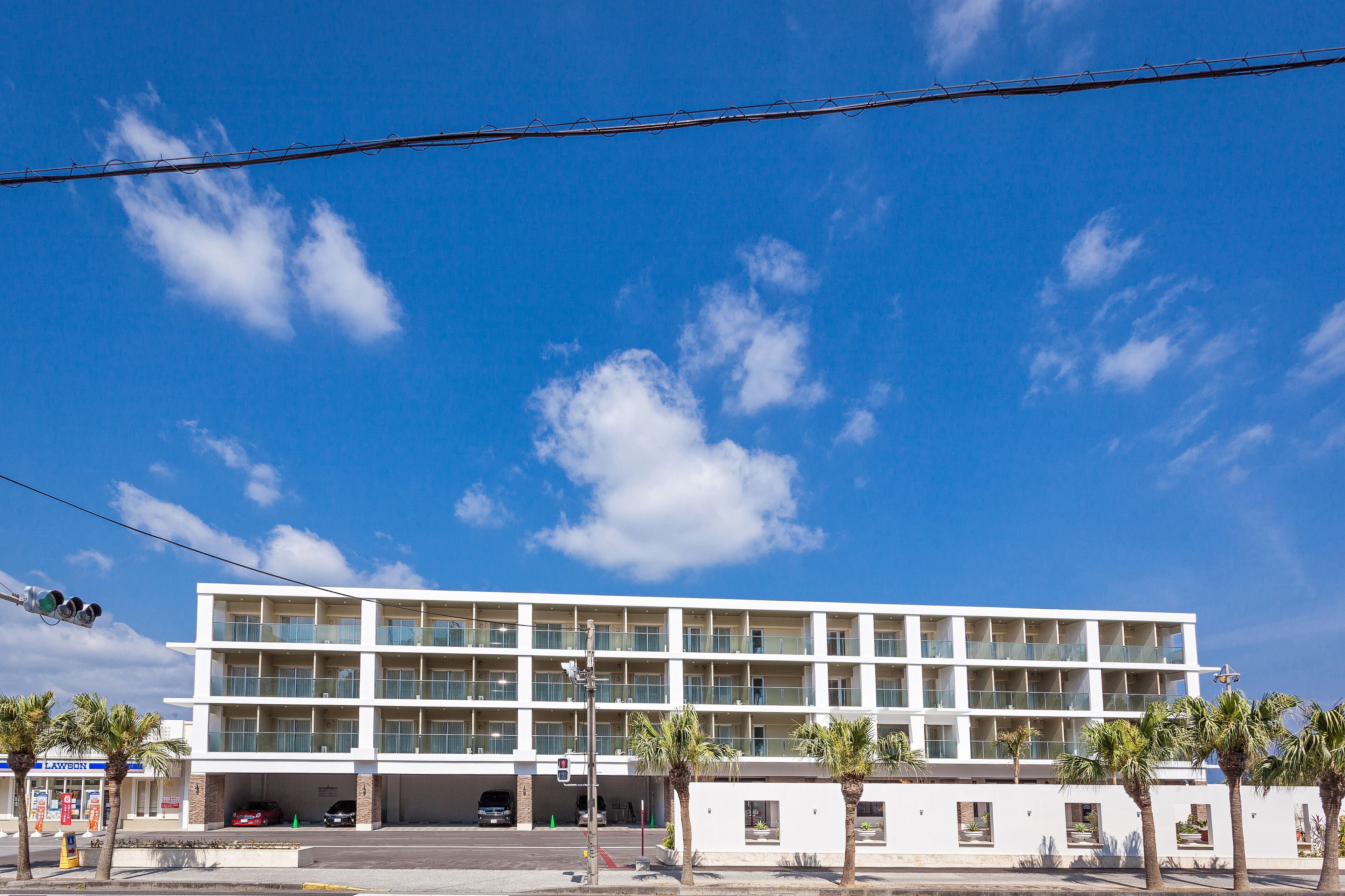 Un hotel de varios pisos con fachada plana, grandes ventanales y un aparcamiento en la base.