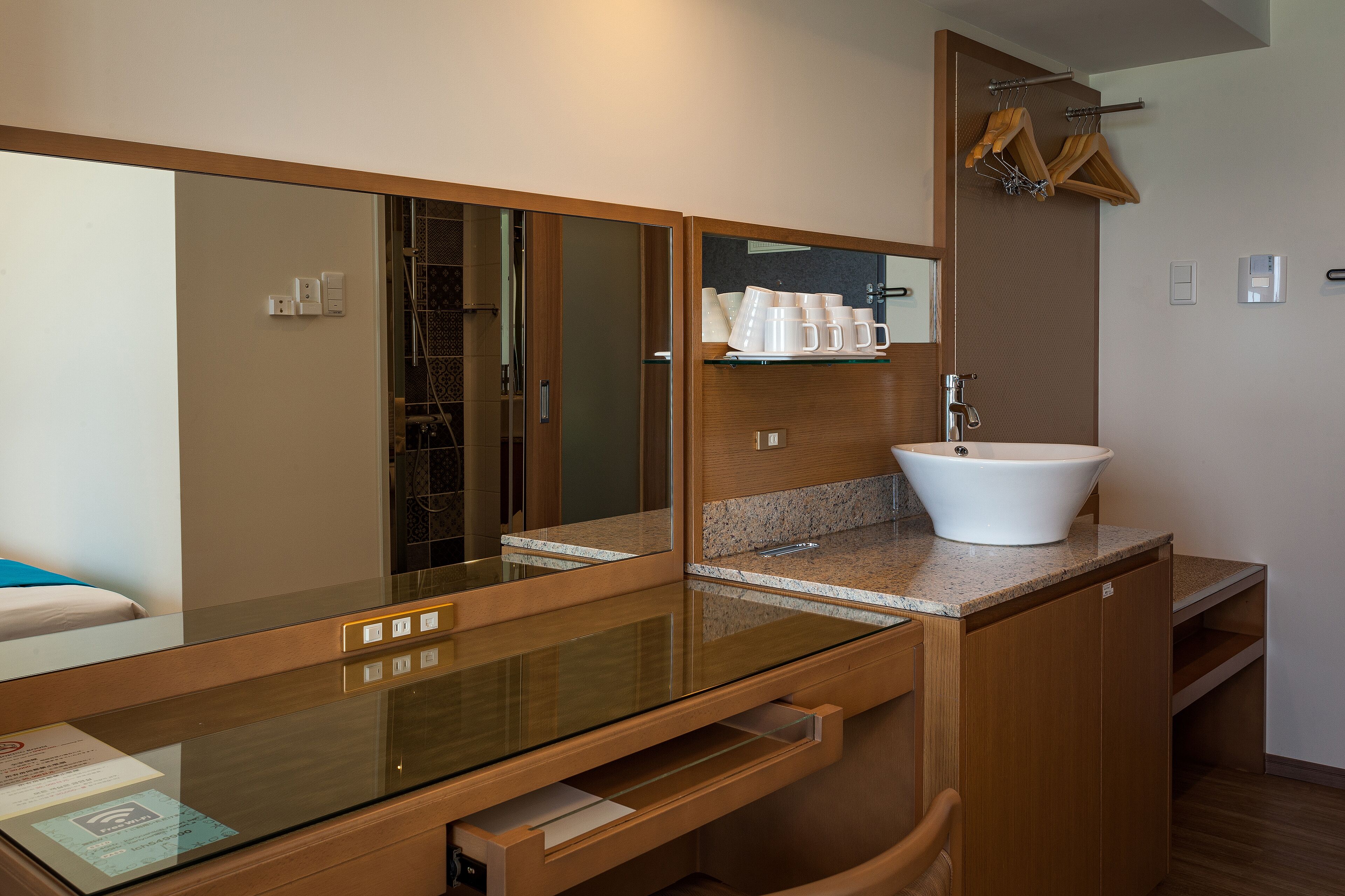 A modern bathroom with a glass-enclosed vanity, a white sink, and a large mirror.