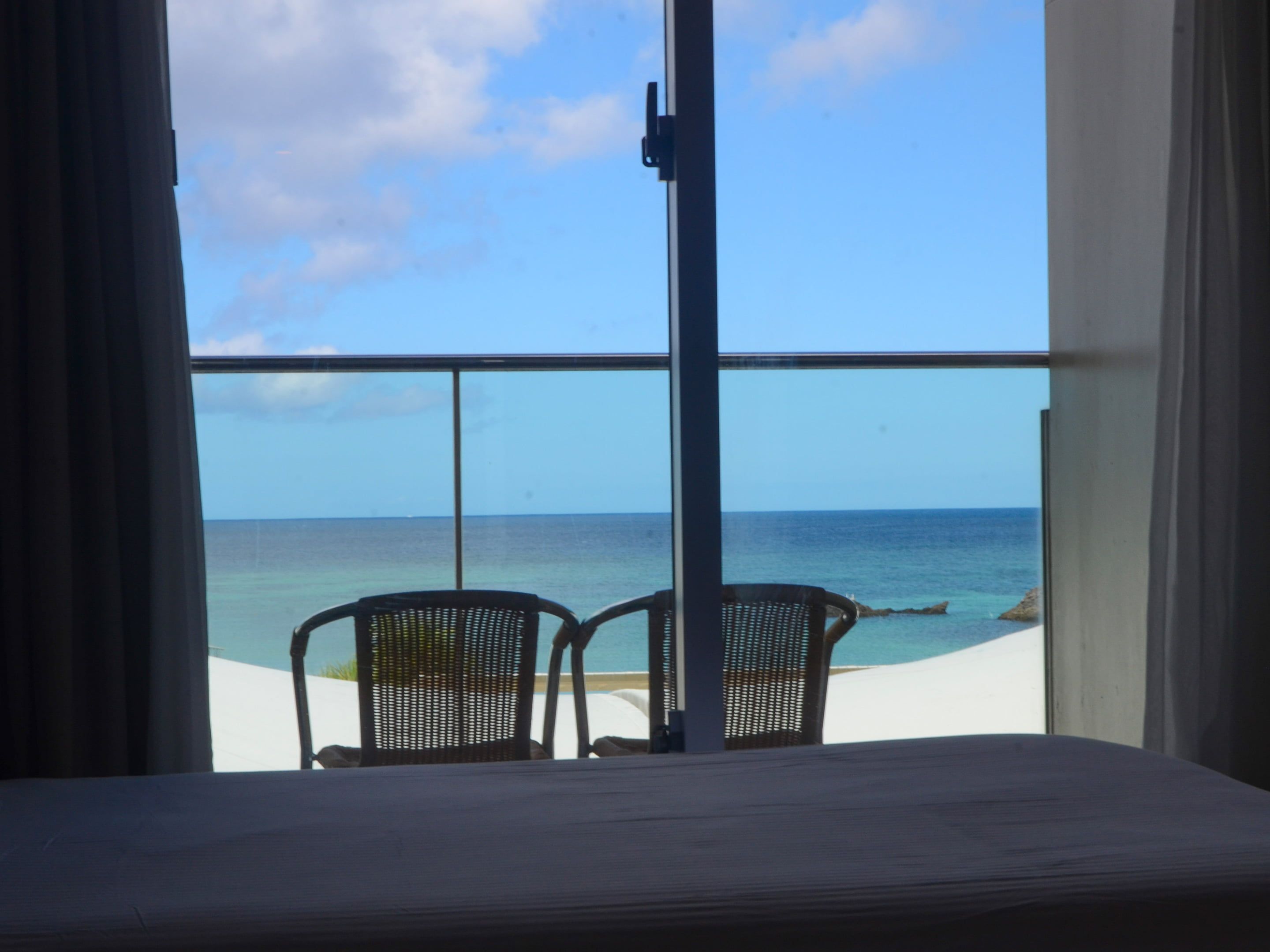 A balcony with two chairs facing the ocean.