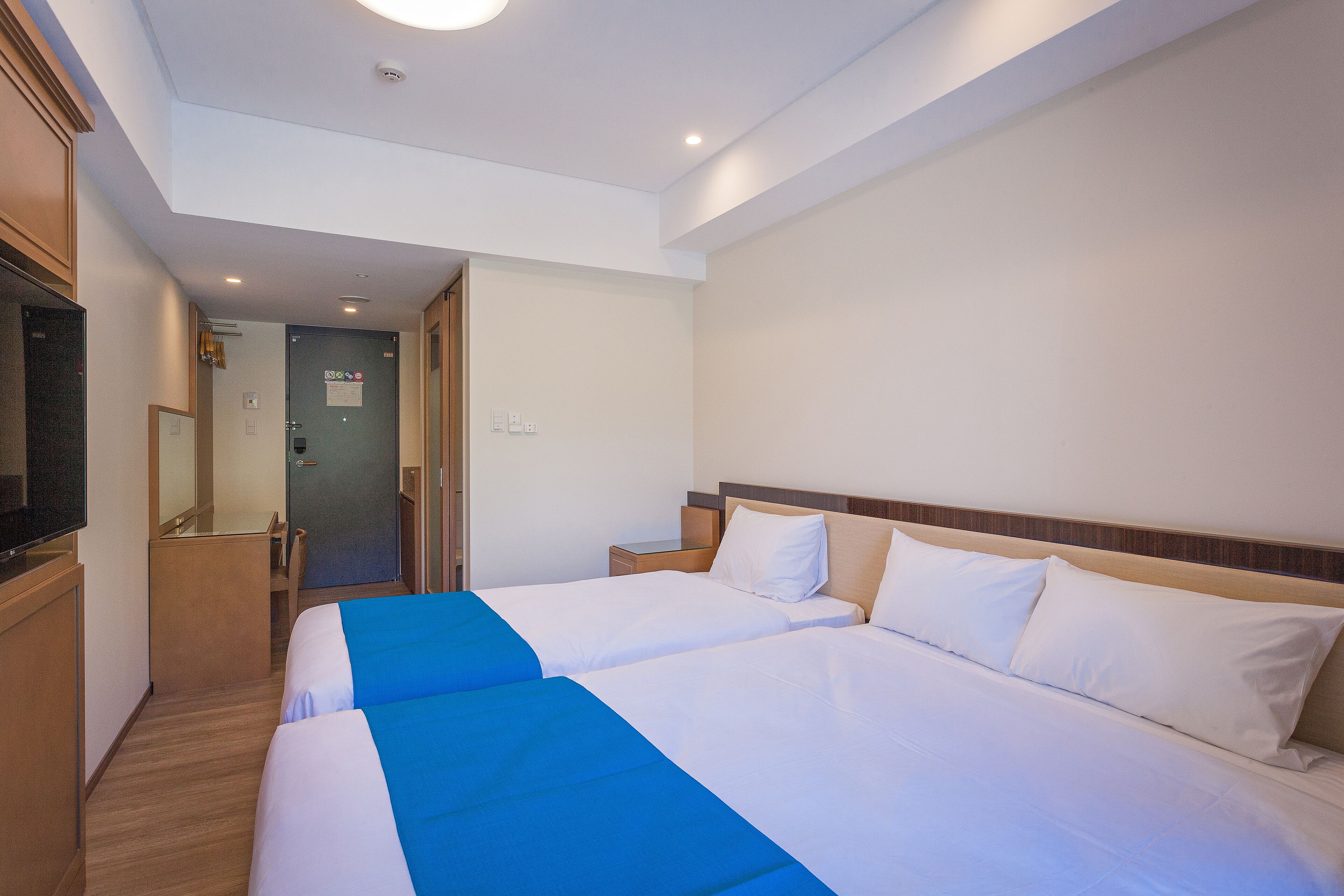 Una habitación de hotel con dos camas, un televisor y un espejo.