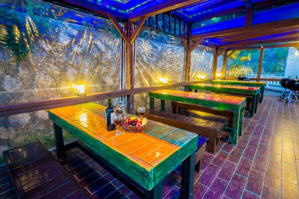 Un espacio al aire libre con mesas y bancos de madera, algunos con botellas y vasos.